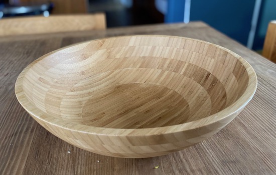 A large bamboo salad bowl sitting on a wooden table