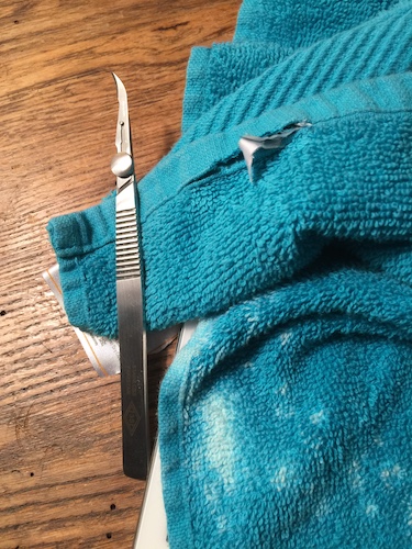 A teal blue cotton bath towel getting its rayon tag removed