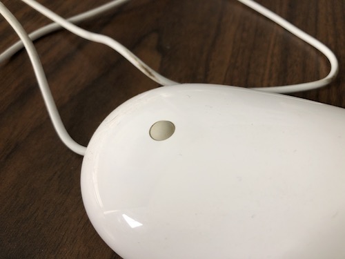 Close up of a white mouse with a gray rubber scroll knob on a table