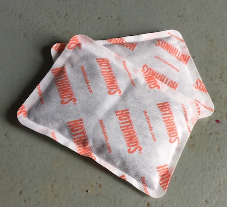 A pair of one time use hand warmers sitting on a gray floor