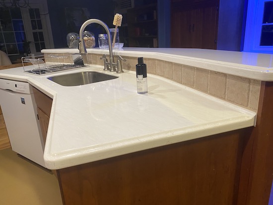 A shiny white countertop with a bottle of sealer sitting on it