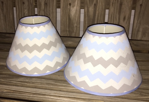 Two light blue, white and gray patterned lamp shades on a wooden bench