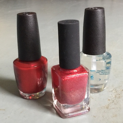 Three bottles of nail polish, two red and one clear coat