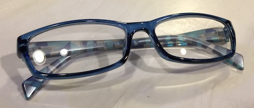 A pair of plastic blue reading glasses sitting on a white countertop
