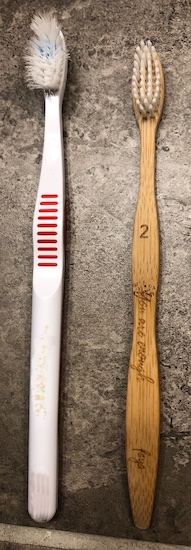 A plastic polystyrene toothbrush next to an all natural bamboo toothbrush