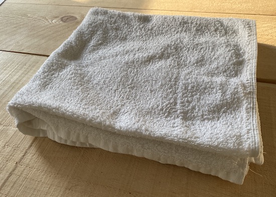 A folded white cotton towel sitting on a wooden table