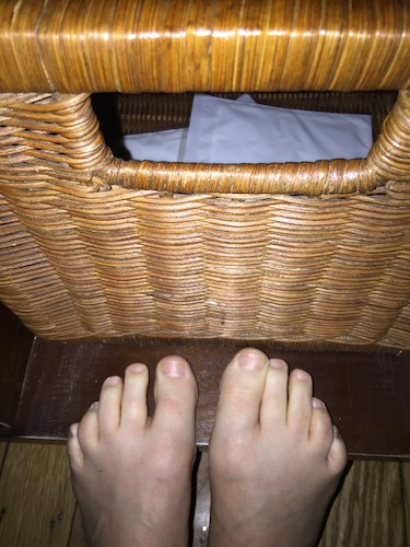 Bare feet on the ledge of a coffee table wicker drawer side out with packages of hand warmers in the basket