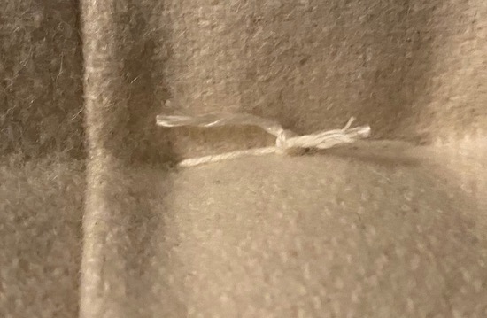 A white string tied in a knot on a cushion