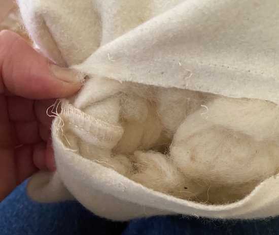 The inside stiching of a white wool pillow stuffed with organic wool